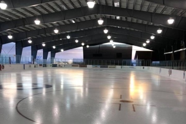 Image of hockey rink at twilight with the lights on