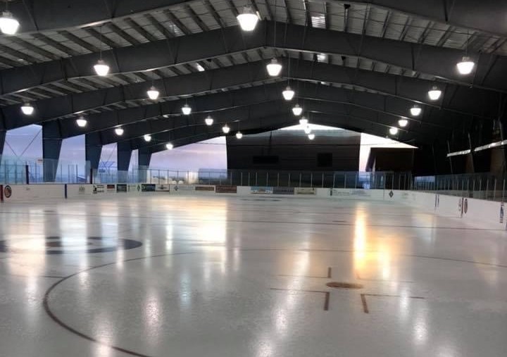 Image of hockey rink at twilight with the lights on